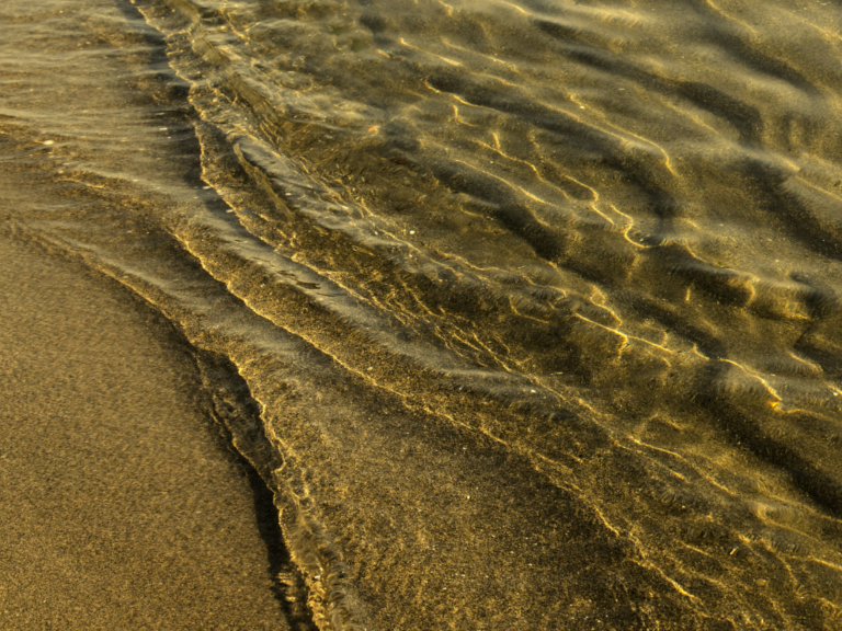 Leichte, auslaufende Wellen am Strand